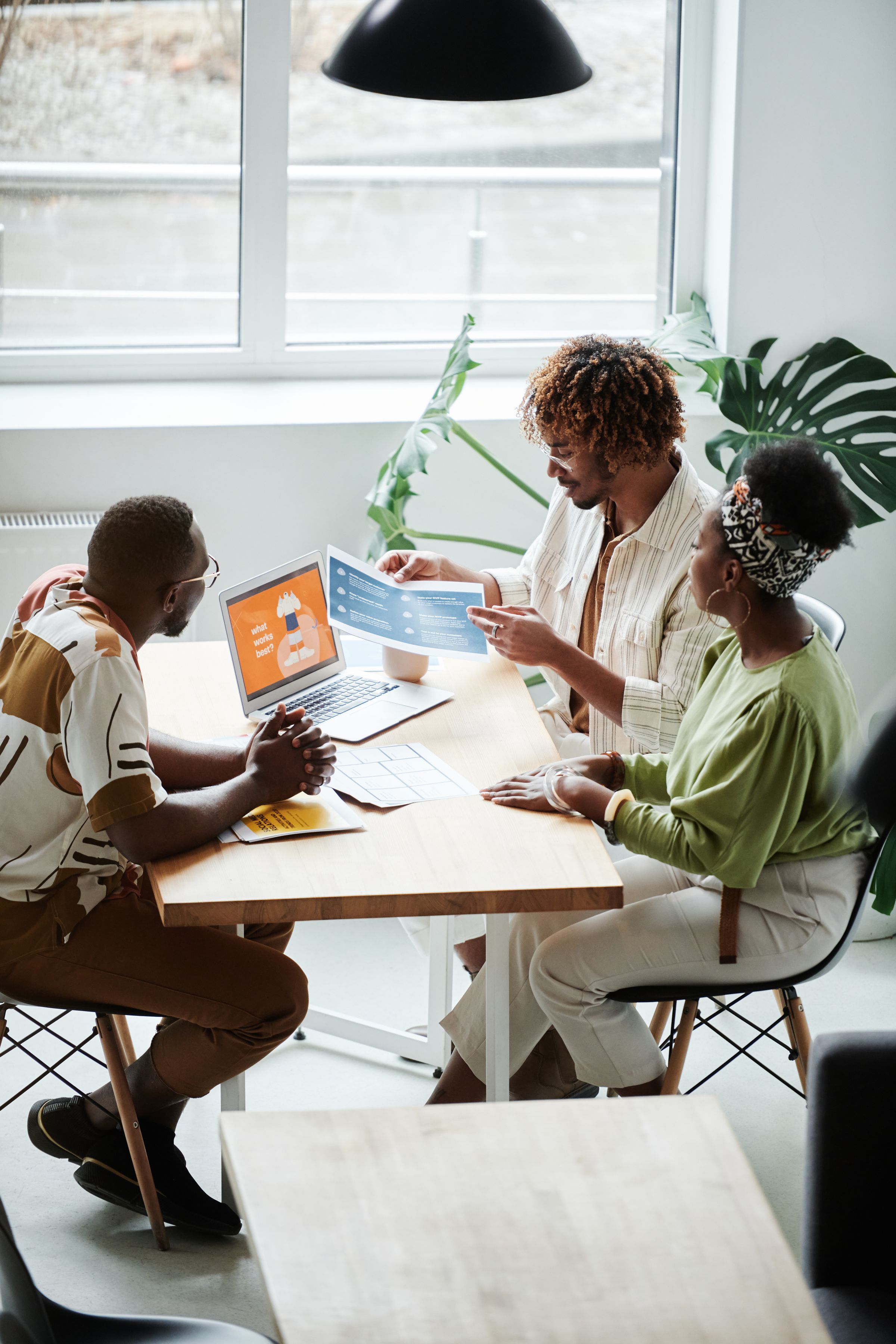 Colleagues discussing documents and digital tools around a meeting table