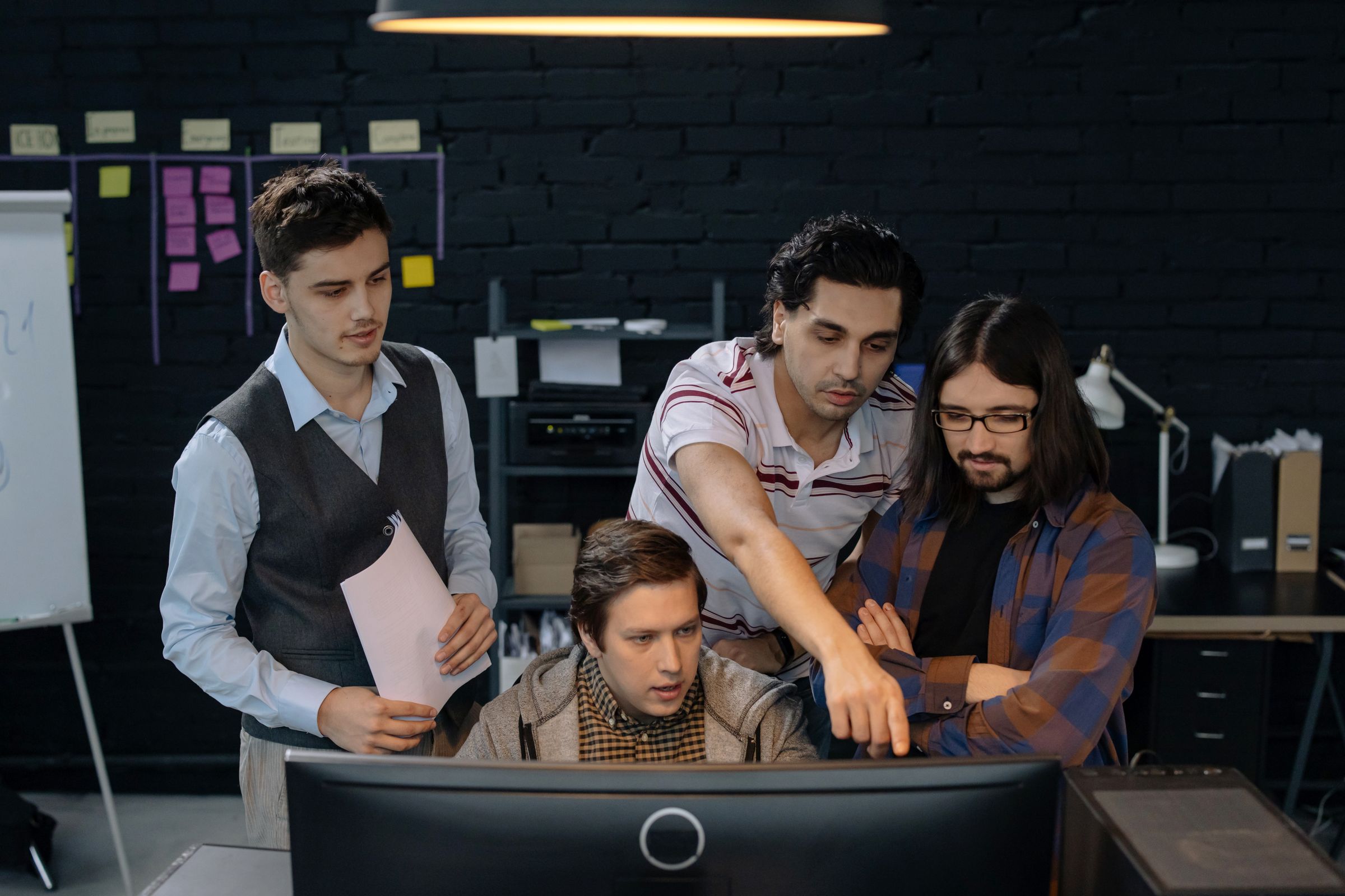A technical team discussing work at a computer